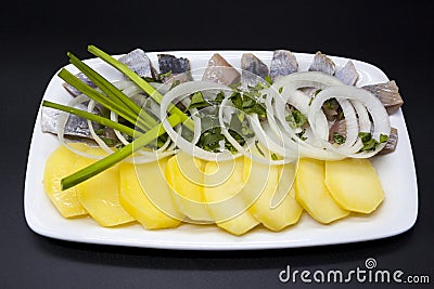 Dutch national appetizer, herring with onions. Tasty pieces of Icelandic herring with boiled potatoes and onions on the plate. Stock Photo