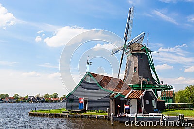 Dutch typical landscape. Traditional old dutch windmill against blue cloudy sky in the Zaanse Schans Stock Photo