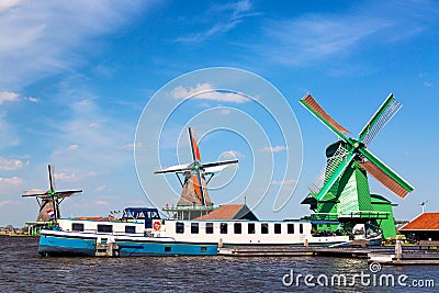 Dutch typical landscape. Traditional old dutch windmills with cruise ship and blue sky in the Zaanse Schans village, Netherlands. Editorial Stock Photo
