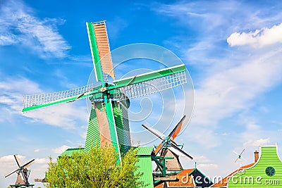 Dutch typical landscape. Traditional old dutch windmills with house and against blue cloudy sky in the Zaanse Schans village, Neth Stock Photo