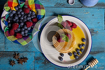 Dutch waffle breakfast with raspberry, blueberry and honey on blue wooden background. Isolated image. aerial shot. Breakfast Stock Photo