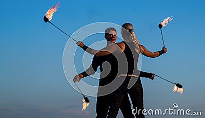 Dynamic fire show. Sexy couple perform poi dance blue sky. Poi performance. Fire dancing. Night party. Holiday Stock Photo