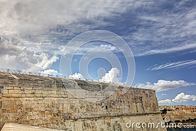 Dynamic HDR photo of cloudy skies and sun behind the clouds and historic city Valletta Stock Photo