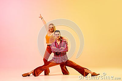 Dynamic image of stylish, talented, emotional couple, man and woman in vintage costumes dancing disco dance against Stock Photo