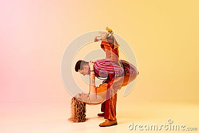 Dynamic image of stylish, talented, emotional couple, man and woman in vintage costumes dancing disco dance against Stock Photo