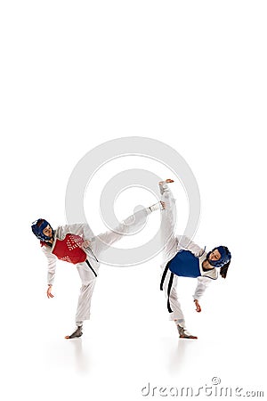 Dynamic image of young girls in helmet and dobok practicing taekwondo stunts, fighting isolated over white background Stock Photo
