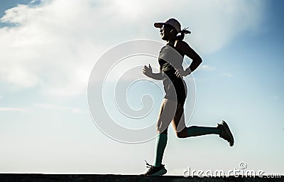 Dynamic silhouette of young attractive and athletic woman in compression running socks jogging happy on city park doing intervals Stock Photo