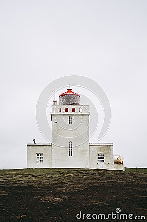 Dyrholaey lighthouse under heavy gray sky. Stock Photo