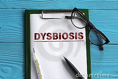 DYSBIOSIS - word in a notepad on a blue background with a pen, glasses and a thermometer Stock Photo