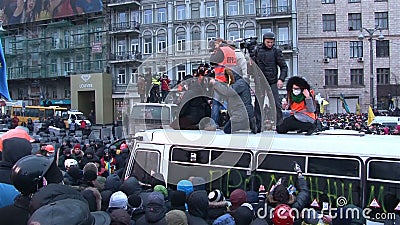 Dziennikarzi stoi na łamanym autobusie wśród protestującego tłumu z kamerami Dziennikarzi stoi na łamanym autobusie wśród protestującego tłumu z kamerami
