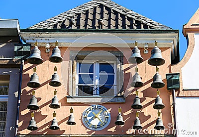View on old house facade with many antique bells and clock against blue sky Stock Photo