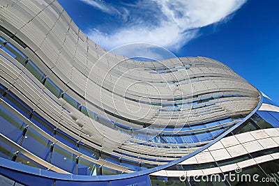 Ow angle view on curved steel, glass, natural building facade with wavy lines against clear blue sky Editorial Stock Photo