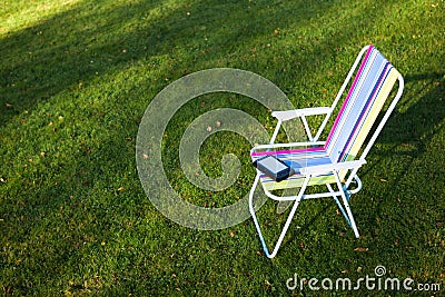 E-Book reader on the chair, green grass background Stock Photo