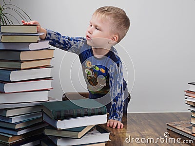 E boy reaches for the stack of books Stock Photo