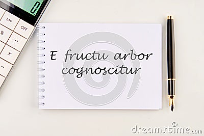 E fructu arbor cognoscitur the phrase in Latin translates as the Tree is known by its fruits on a white notebook Stock Photo