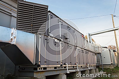Side view of the gray commercial central conditioner with DX coil and big condensing unit standing outdoor on the ground covered b Stock Photo