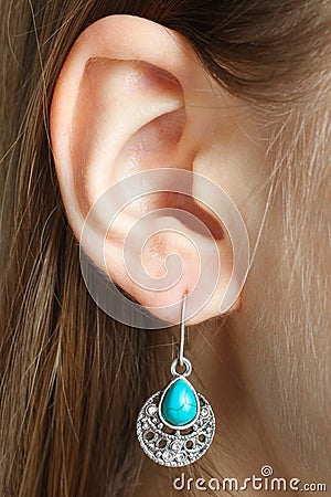 Ear with a beautiful earring with a turquoise stone Stock Photo