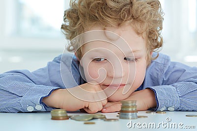 Early financial education concept. Boy looking at a stack of coins. Stock Photo