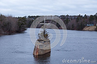 Early grey spring morning view of a large metal catholic cross on former Gouin bridge pillar in the Jacques-Cartier River Stock Photo