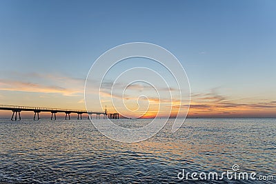 Early morning a few minutes before sunrise. Dawn on the sea with pontoon. Blue sky is painted in shades of orange. Stock Photo