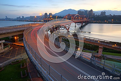 Early morning view of car trails on a curved highway bridge over beautiful Tamsui River in Taipei City,Taiwan Stock Photo