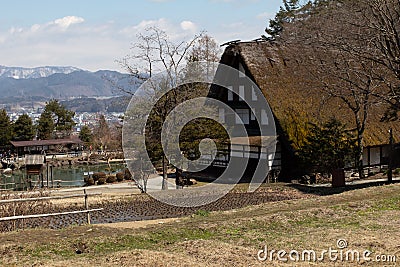 Early spring scenic landscape photograph of a traditional thatched roof house in rural Japan next to a rice paddy Stock Photo