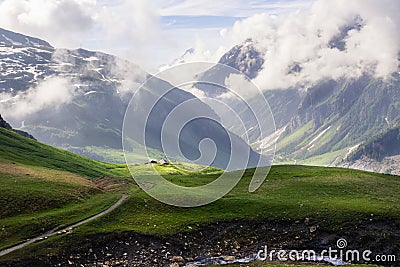 Green Alpine fields and meadows, snowy peaks in the European French Alps Stock Photo