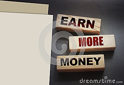 Earn More Money written on a wooden blocks on black. Business career concept Stock Photo