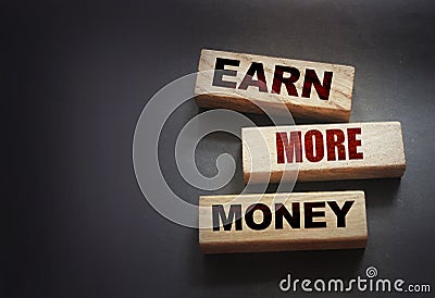 Earn More Money written on a wooden blocks on black. Business career concept Stock Photo