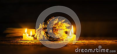 Ears of wheat and lighting candles on dark wooden background Stock Photo