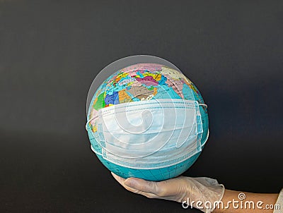 Earth globe dressed in a protective mask on the hands of a man in protective gloves. Stock Photo