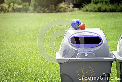 Earth with red heart on the recycle bin in the park, save the world, love and protect our planet, and environmental friendly Stock Photo