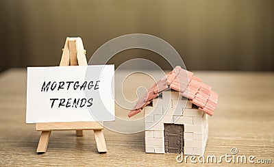 Easel with Mortgage trends concept and a miniature house. Mortgage rates and the latest news about their changes. Housing loan and Stock Photo