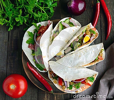 East pita bread with various fillings : meat, salami, egg, cucumber, parsley, tomato, chili pepper, Dijon mustard. Taco. Stock Photo