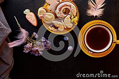 Easter aesthetics homemade cookies, tea cup flat lay with decorations. Holiday food, tea time on black background Stock Photo
