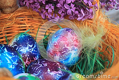 Easter background. Art decorated eggs with lilac and feather in basket Stock Photo