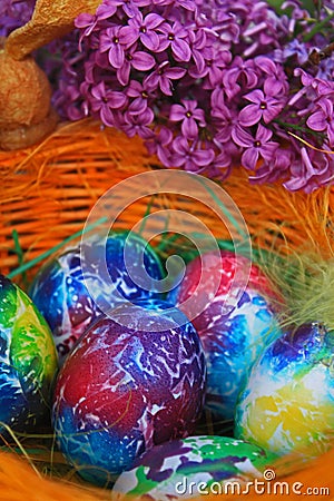 Easter background. Art decorated eggs with lilac and feather in basket Stock Photo
