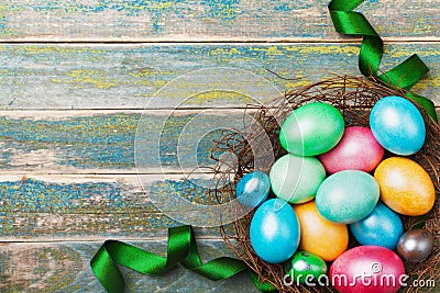 Easter background with colorful eggs in nest decorated with green satin ribbon. Copy space for greeting text. Top view. Stock Photo