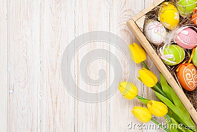 Easter background with colorful eggs and yellow tulips Stock Photo