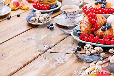Easter breakfast flat lay with fresh coffee, berries and pastries , orange tulips, croissants with bacon and various sweets , Stock Photo