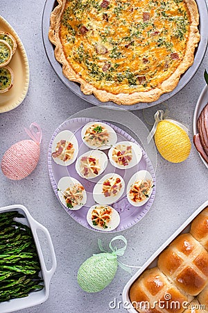 Easter brunch on large table with spiral sliced ham, quiche, deviled eggs and hot cross buns Stock Photo