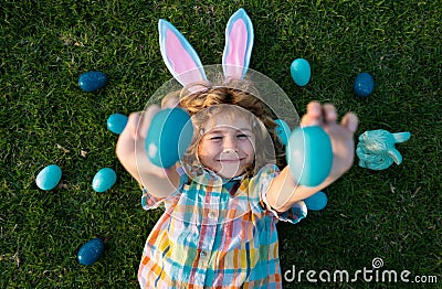 Easter bunny child hunting eggs outdoors Happy Easter day, Kid boy laying on grass in park. Top view funny kids laying Stock Photo