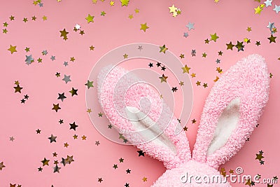 Easter bunny concept. Toy rabbit`s ears with stars confetti on pastel pink background. Flat lay, top view, copy space Stock Photo