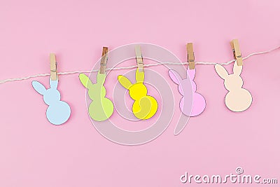 Easter bunny craft paper garland on pink background. DIY holiday handicraft decoration of colorful rabbits. Top view, cutout Stock Photo
