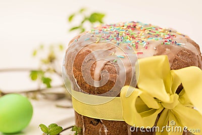 The Easter cake is decorated with a bow of yellow ribbon. On the table are laid out painted eggs Stock Photo