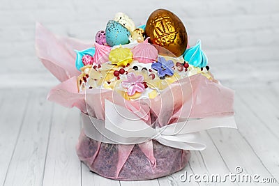 Easter cake with golden and colorful eggs on the top, sophisticatedly decorated, candies, sugar flowers, icing, meringue, and pink Stock Photo