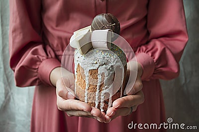 Easter cake in the hands of a young girl in a pink dress. Easter, Easter cake decorated with chocolate products and marshmallows. Stock Photo