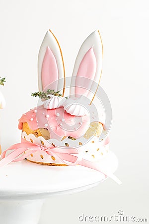Easter cake, sweet bread decorated with bunny ears cookies, sugar icing and meringues. Kulich wrapped in a craft paper on the Stock Photo