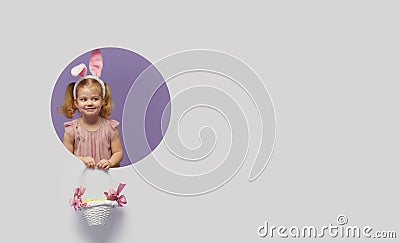 Easter card. Cute little child girl with bunny ears holding basket of Easter eggs. Child in a round hole circle in colored purple Stock Photo