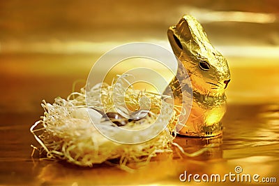 Easter chocolate rabbit and eggs on gold background Stock Photo